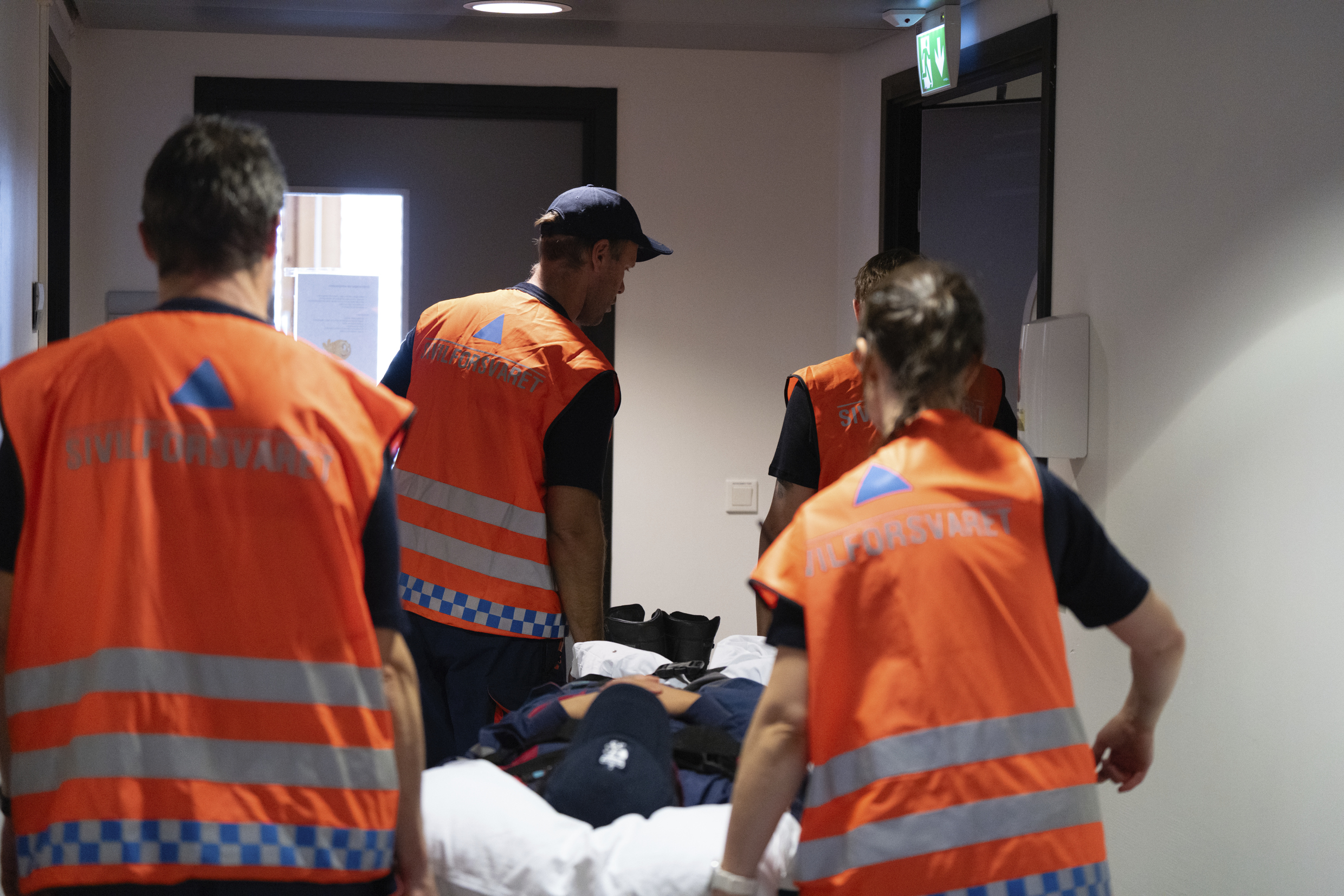 Sivilforsvarsmannskaper med refleksvester bærer en båre under øvelse